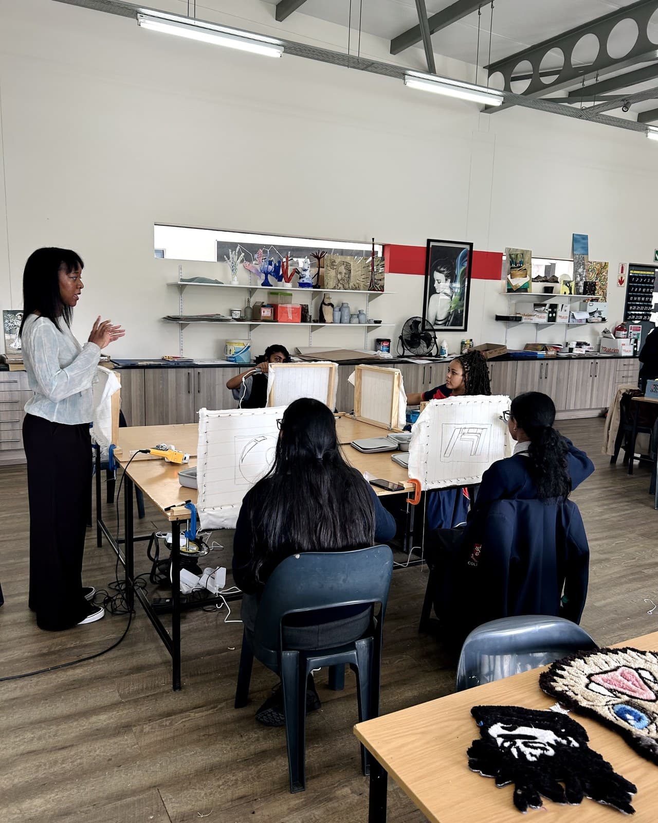 An instructor guiding students through a tufting workshop in a school classroom