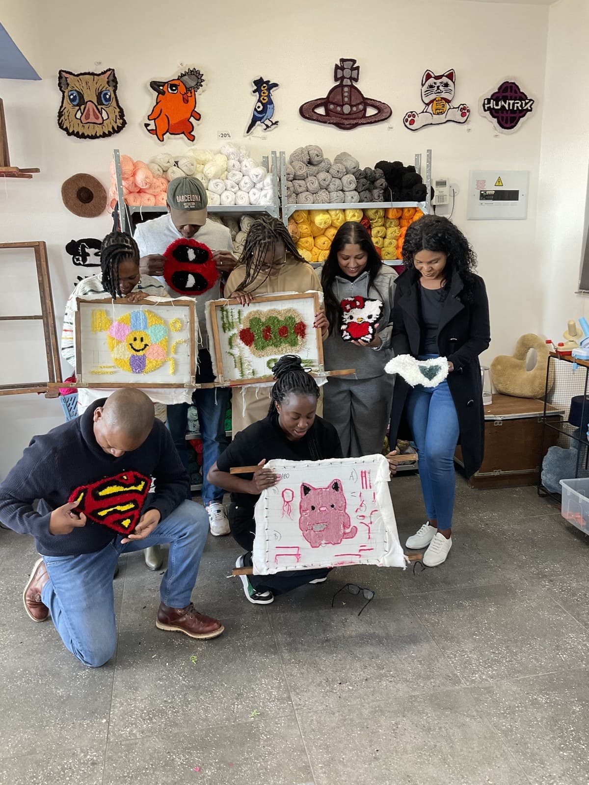 A team holding up the tufted patches they made together at a team-building workshop