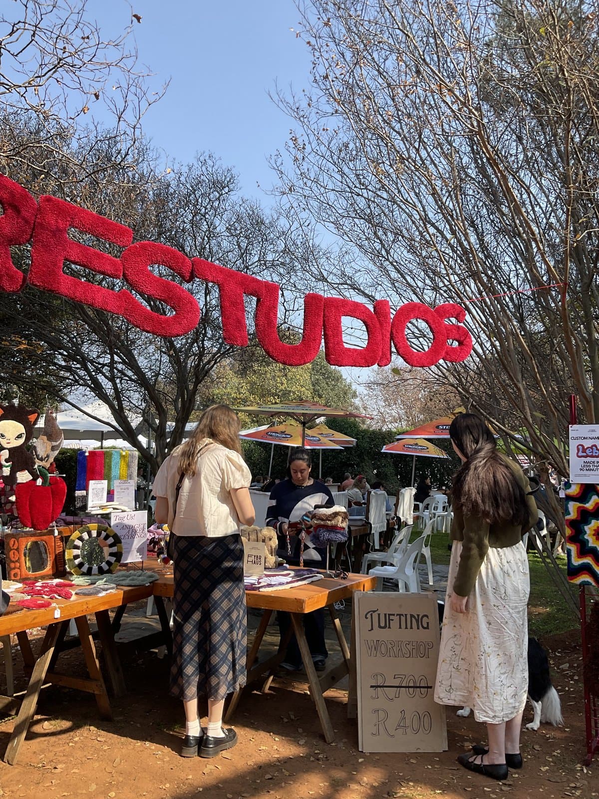 Fybre Studios banner strung between trees at an outdoor market