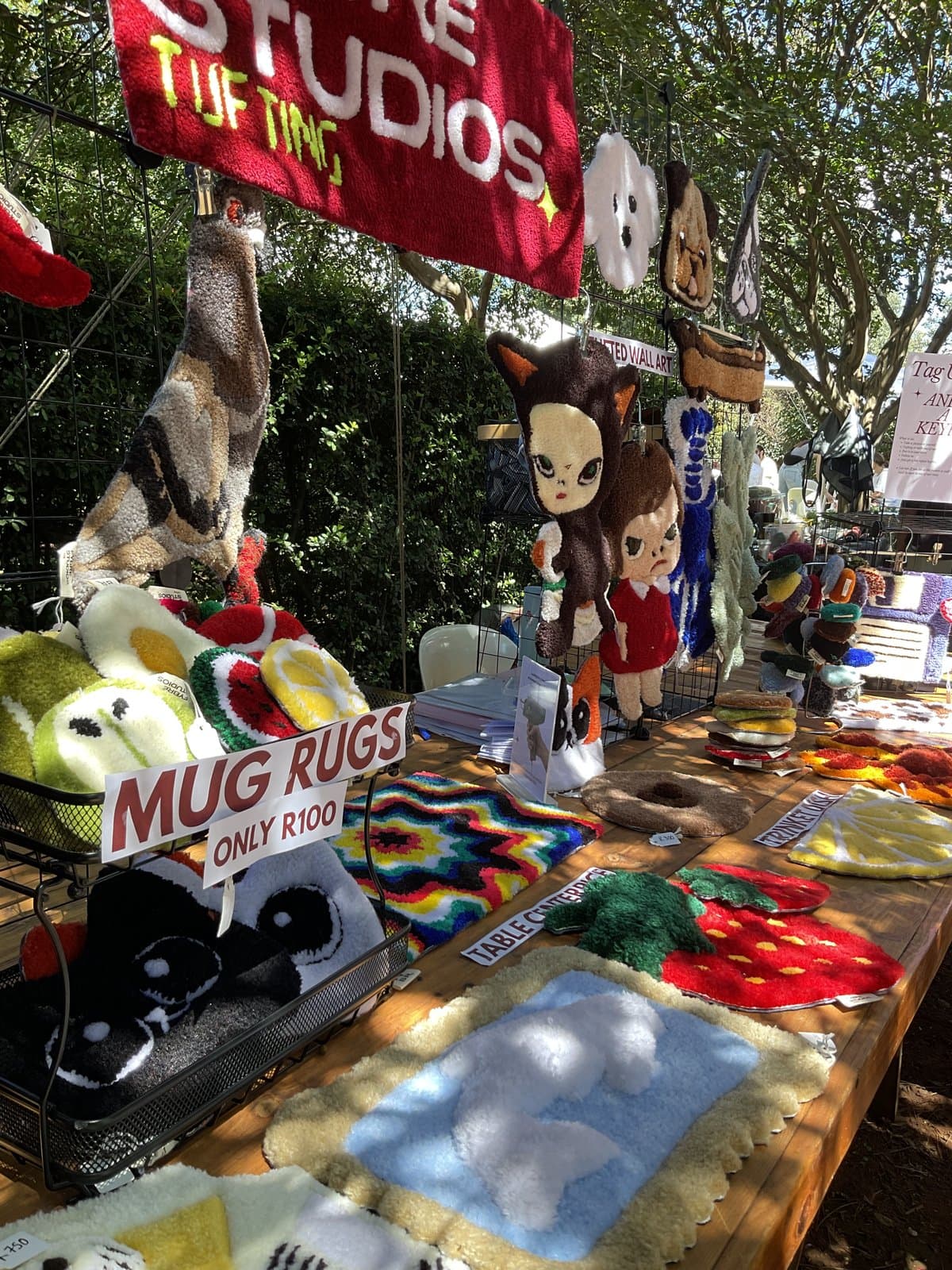 Outdoor market stall hung with tufted rugs and patches
