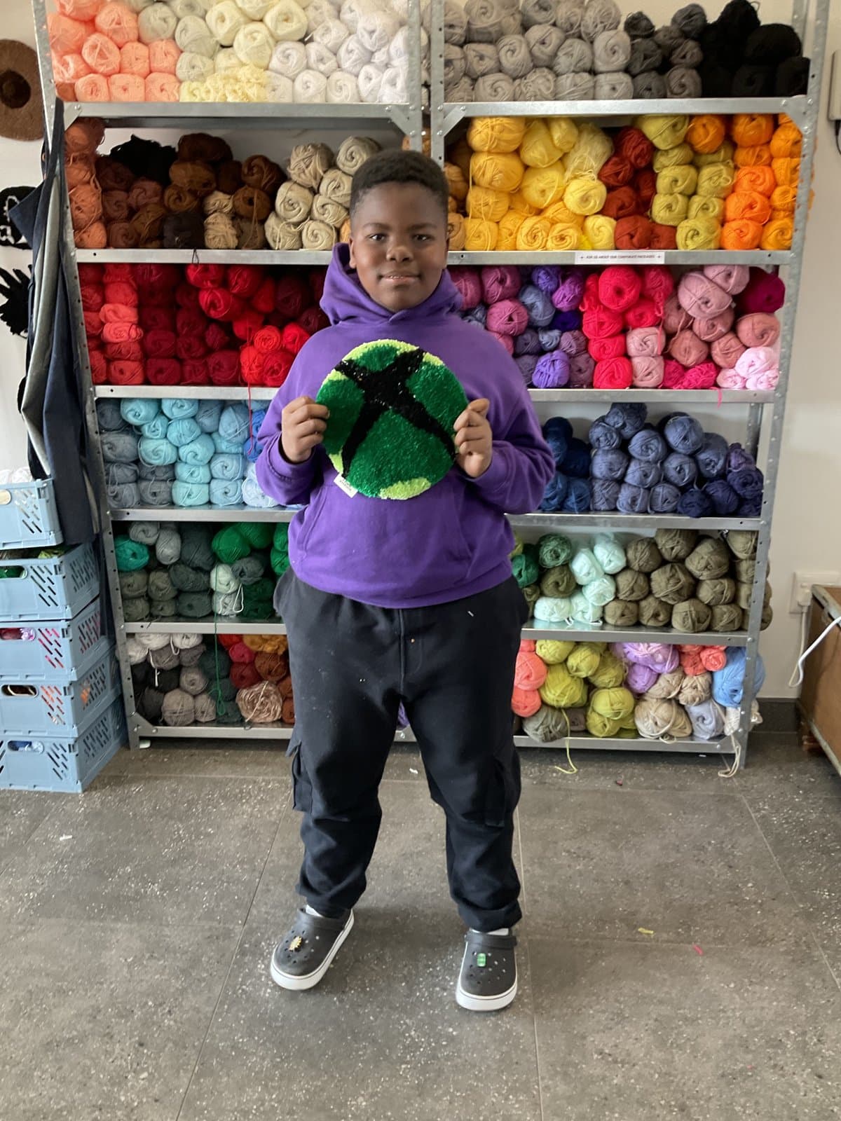 Student holding a green alien-shaped tufted rug