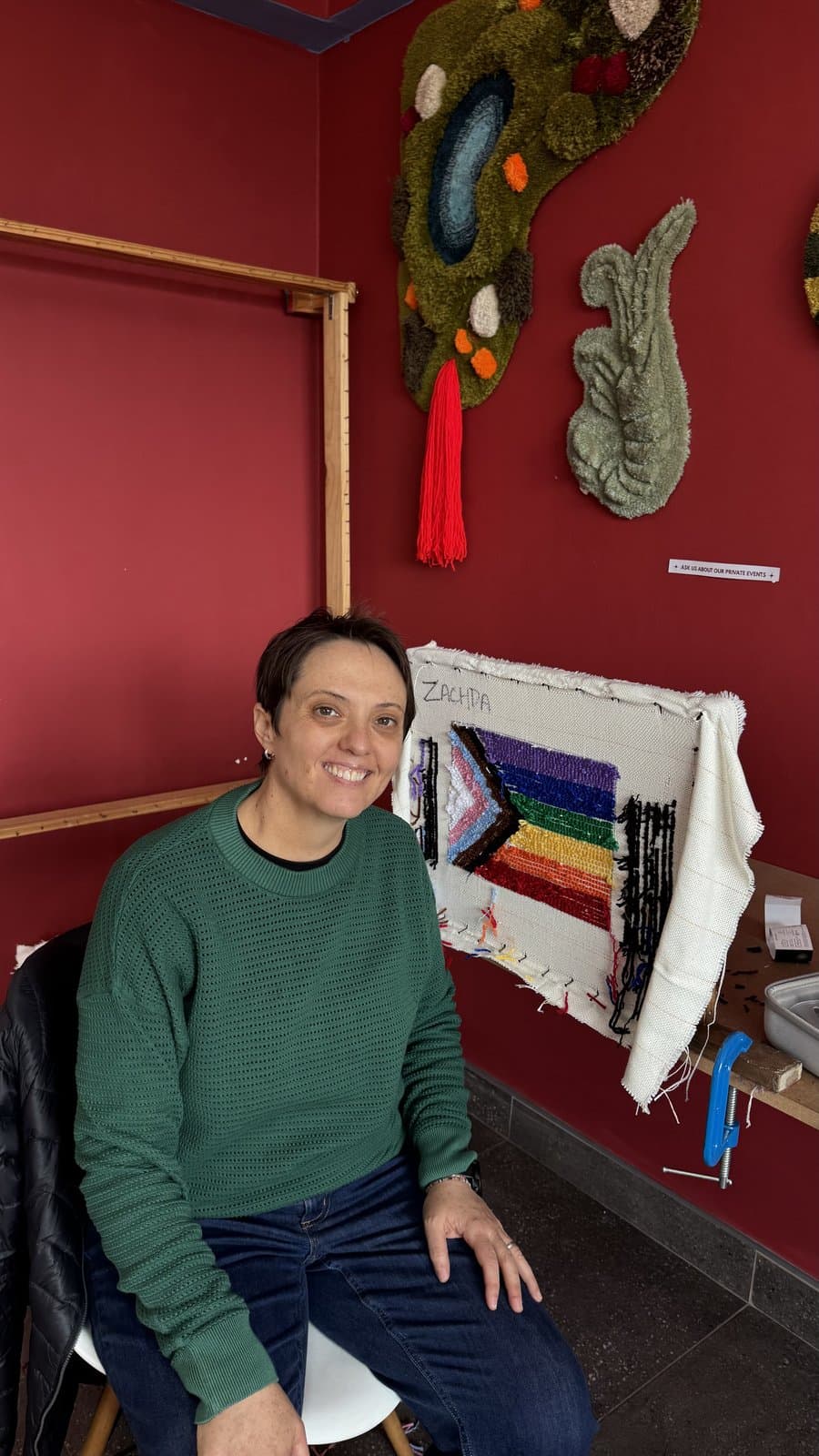 Student seated beside a rug still on its tufting frame