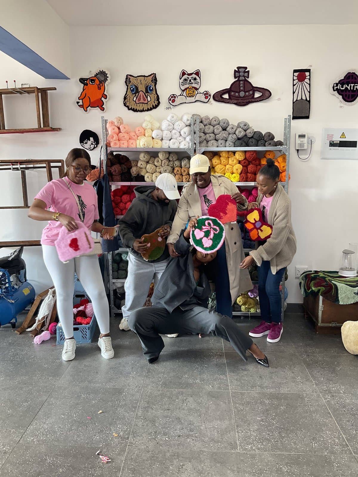 Students posing playfully with their finished tufted artwork
