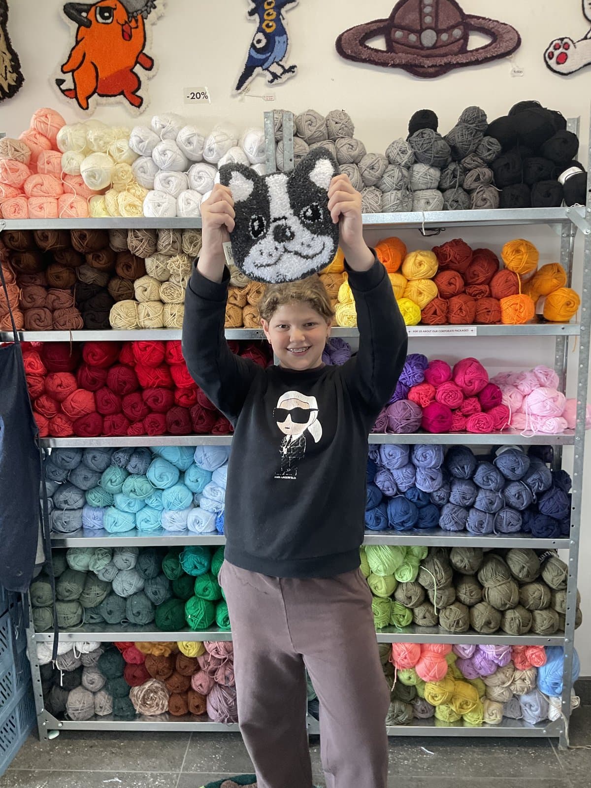 Student posing cheerfully in front of the studio's yarn wall