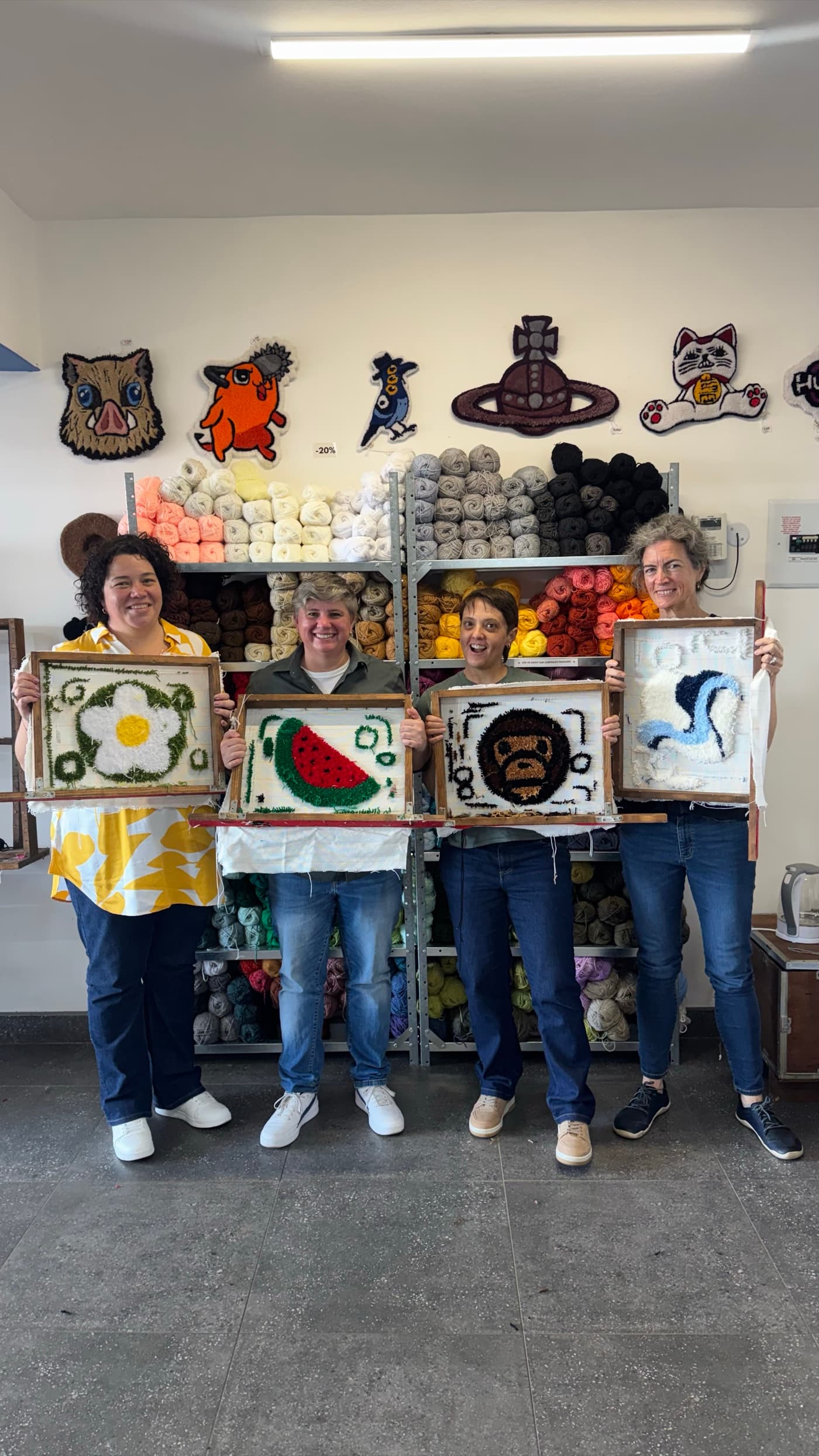 A group of guests holding the mini rugs they made at a Fybre Studios workshop